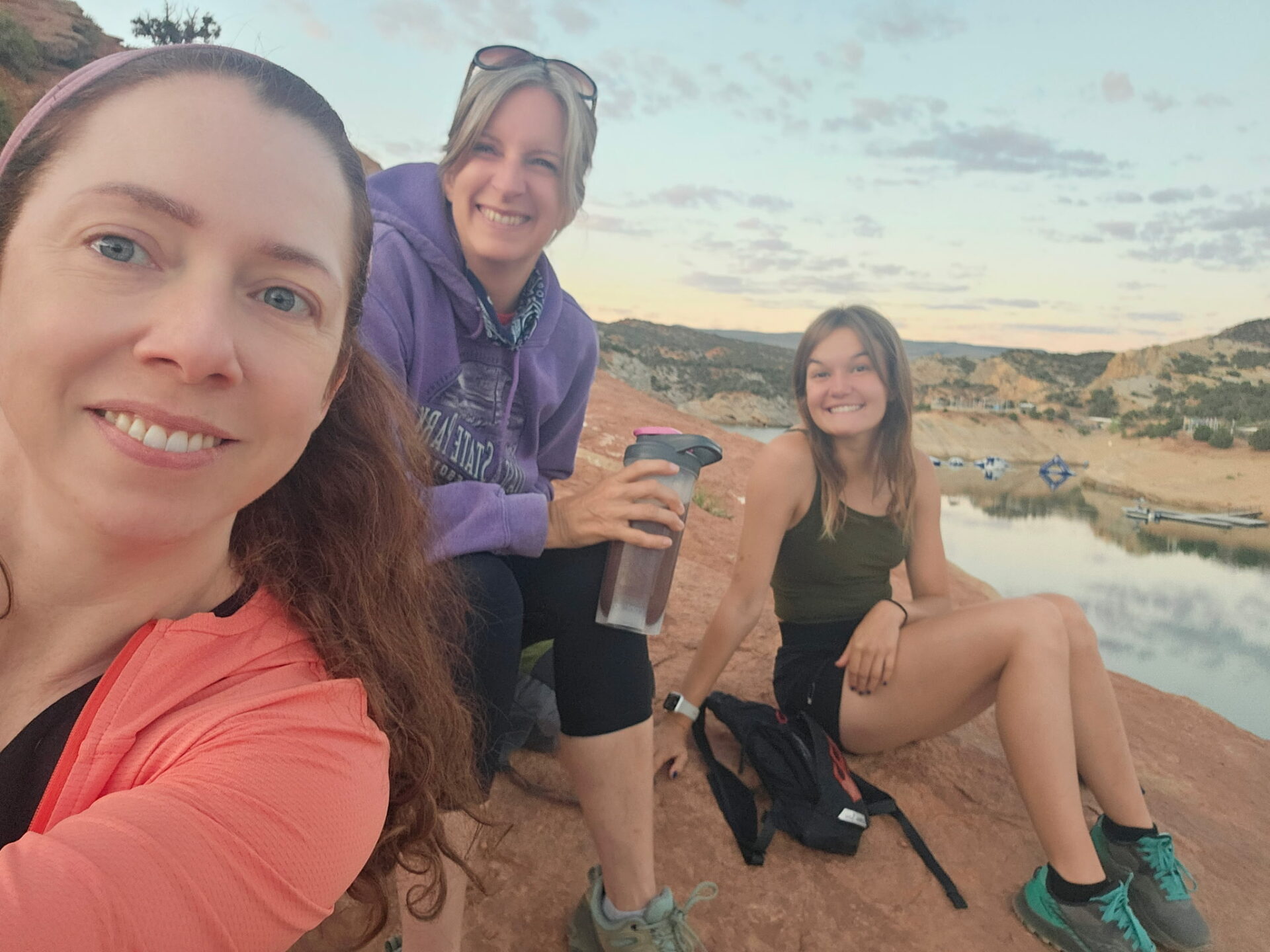 Three women rest on the shore of Red Fleet during a hike.